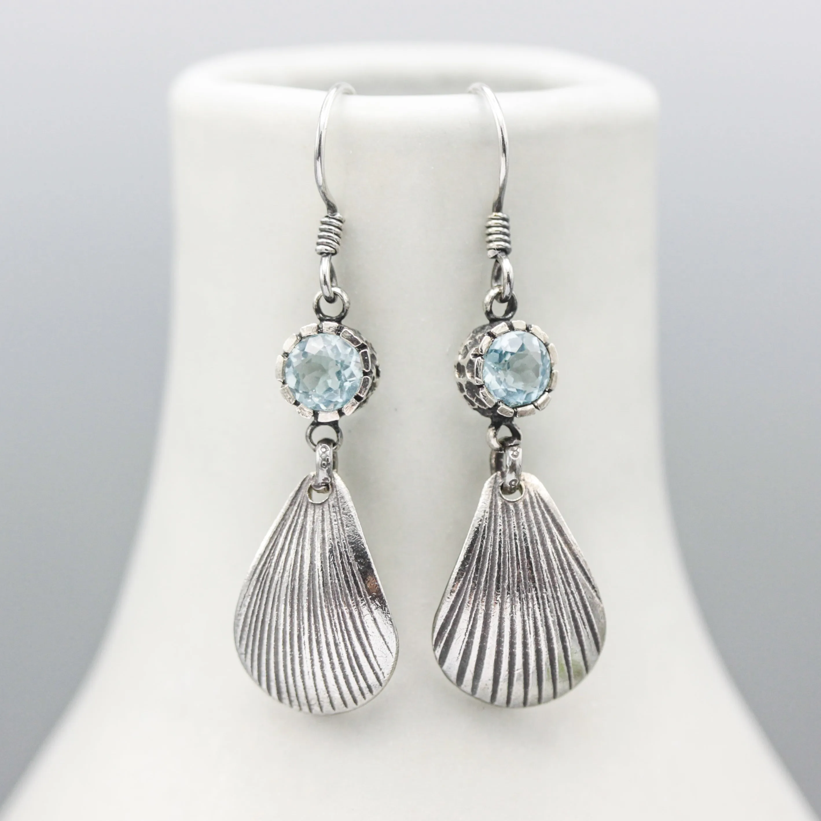 Blue topaz earrings in silver bezel setting with sterling silver shell shape on silver hooks style