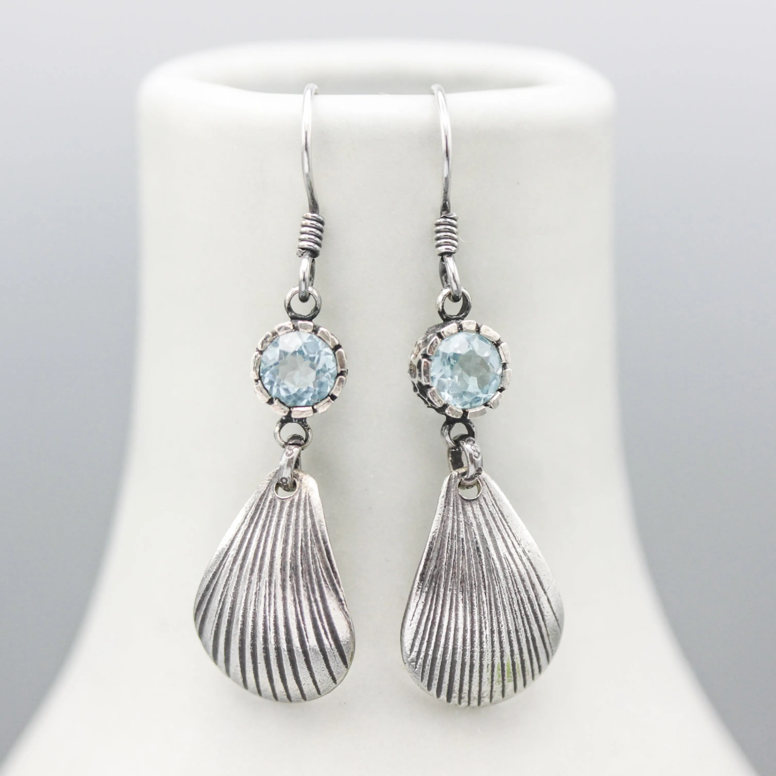 Blue topaz earrings in silver bezel setting with sterling silver shell shape on silver hooks style