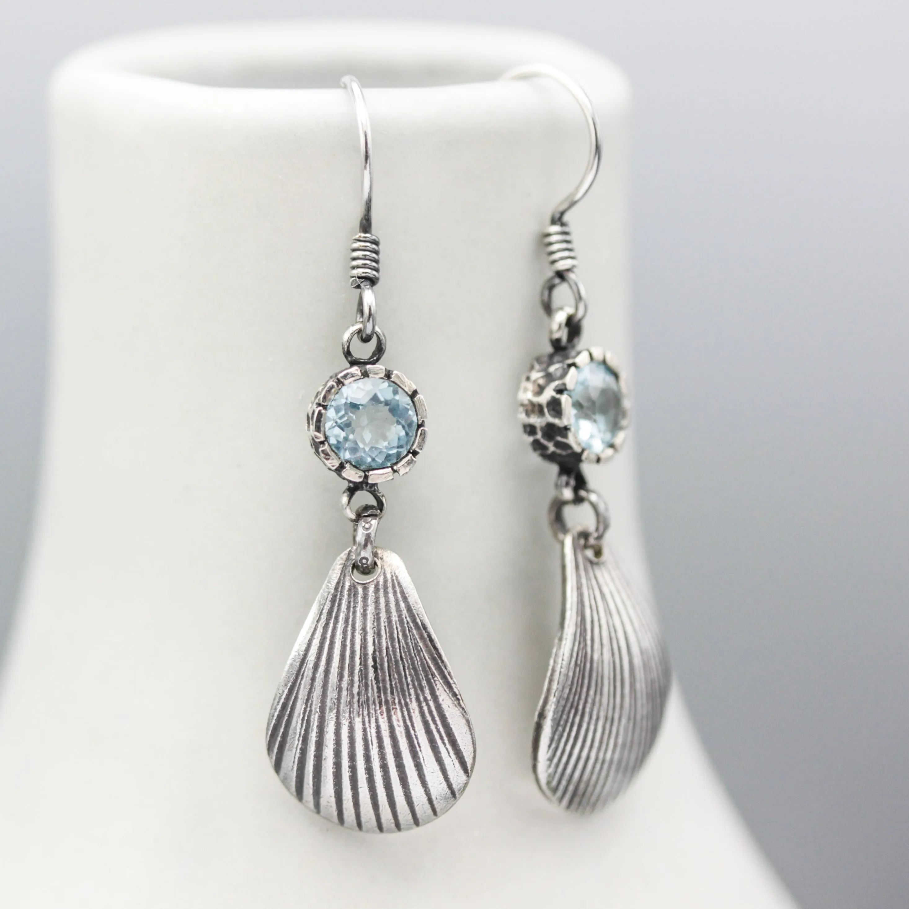 Blue topaz earrings in silver bezel setting with sterling silver shell shape on silver hooks style