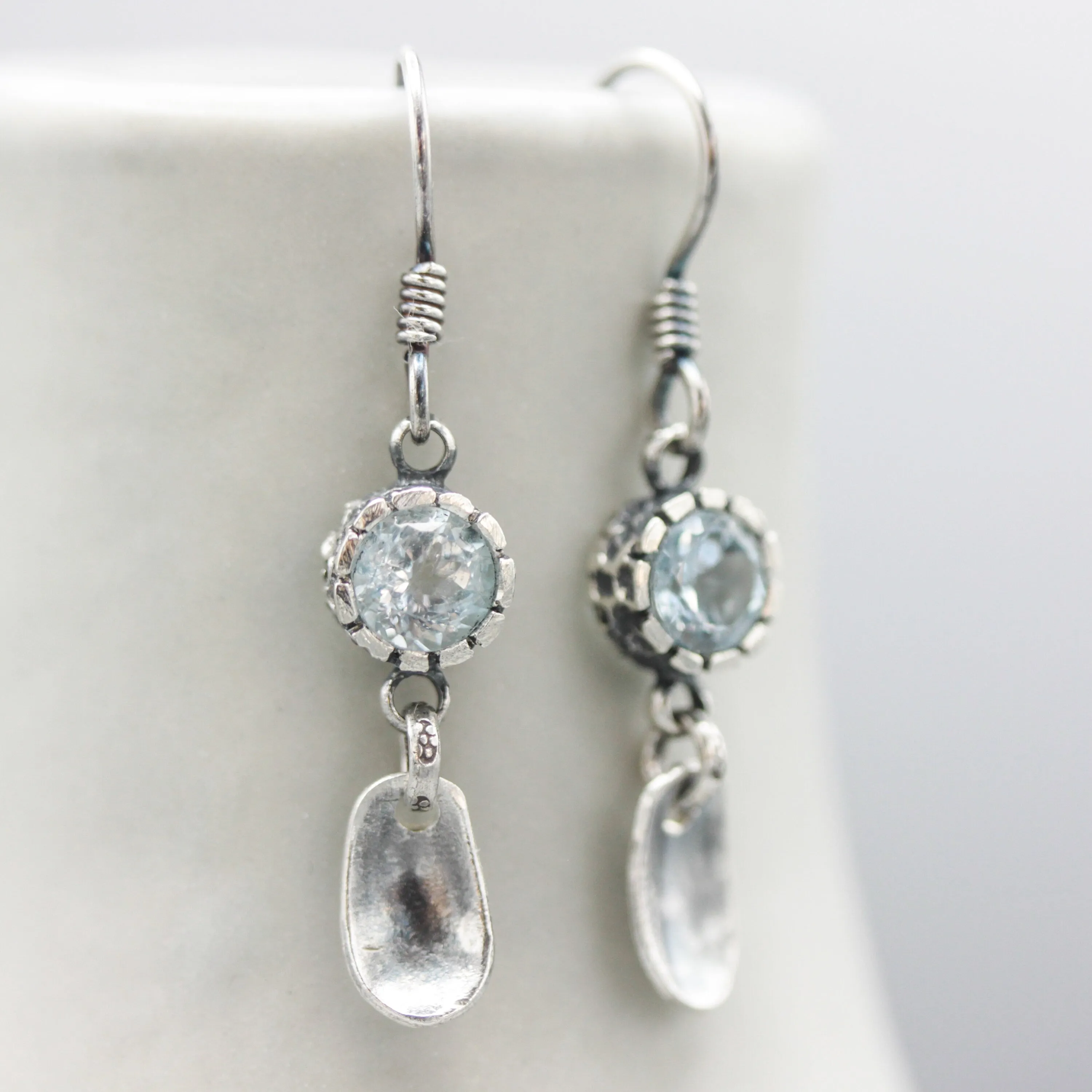 Round blue topaz earrings in silver bezel setting with silver leaf on sterling silver hooks style