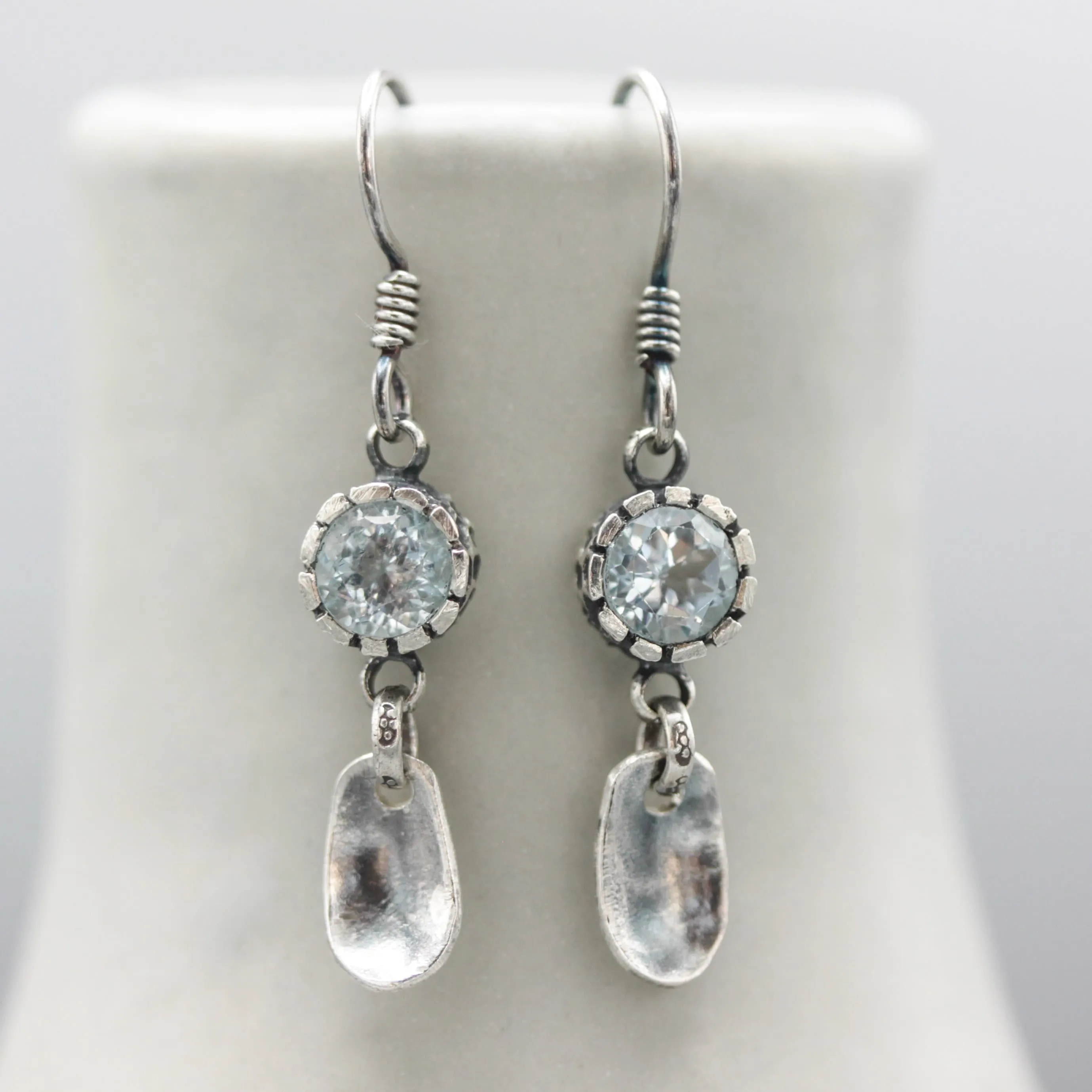 Round blue topaz earrings in silver bezel setting with silver leaf on sterling silver hooks style