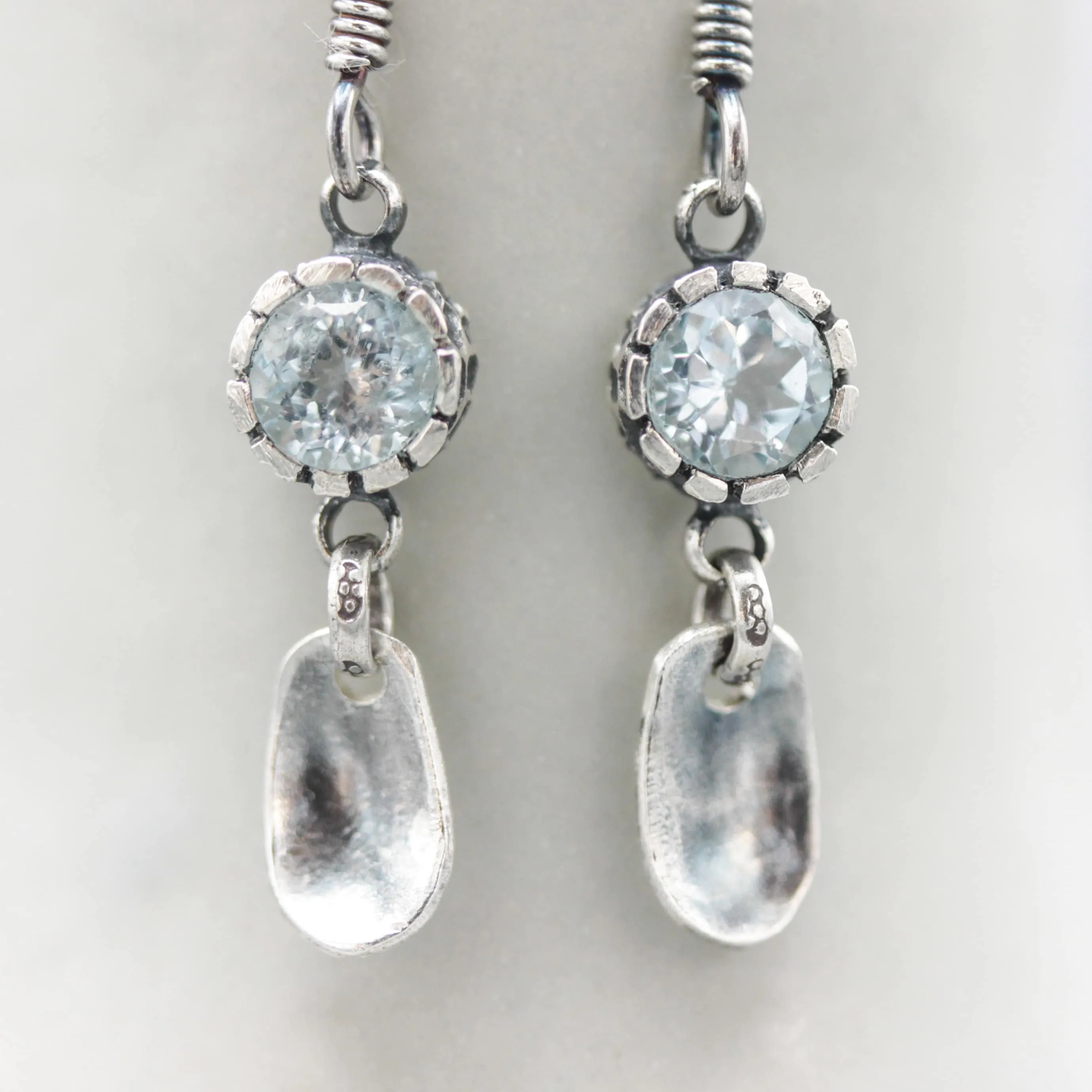 Round blue topaz earrings in silver bezel setting with silver leaf on sterling silver hooks style